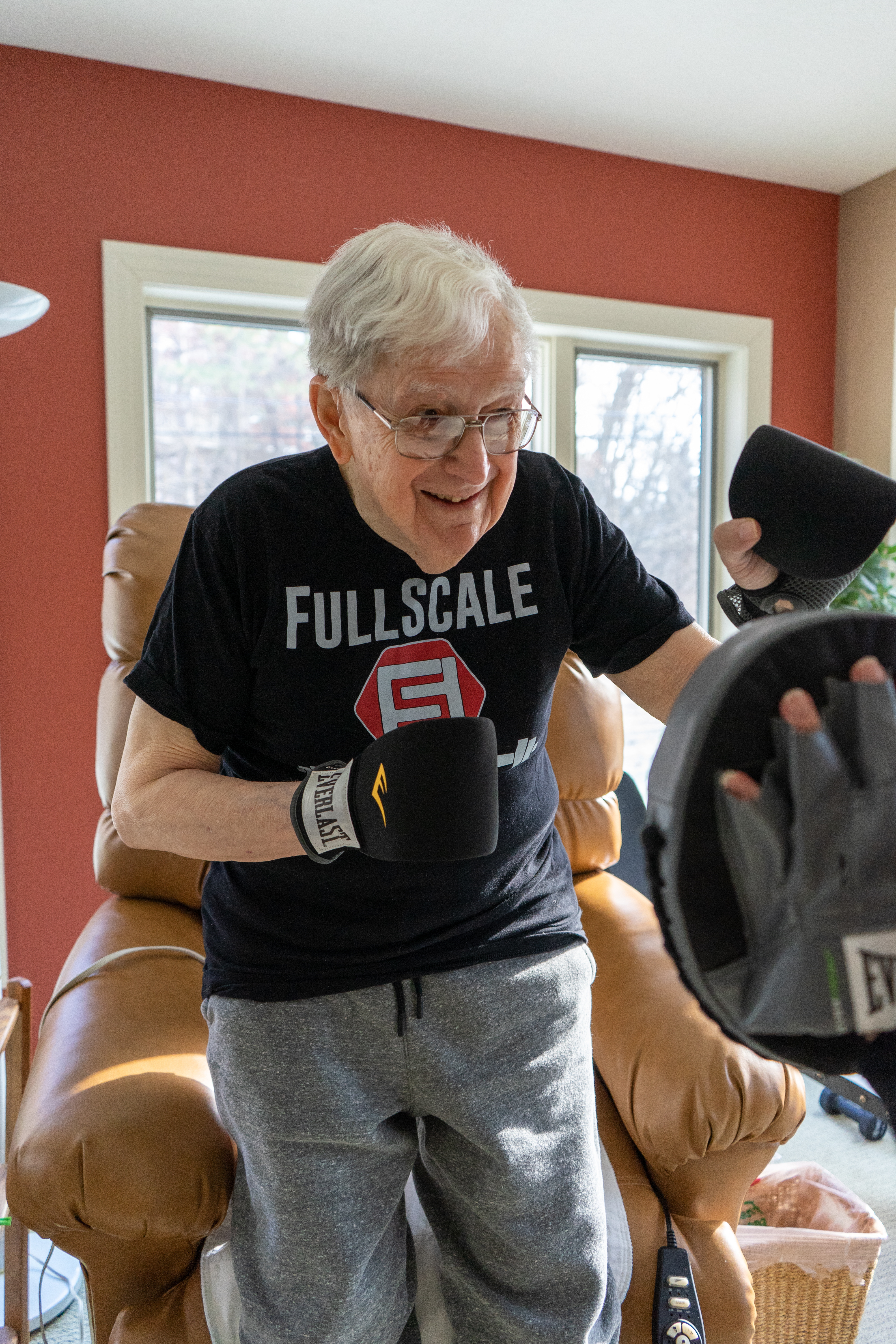 senior citizen is boxing with his local personal trainer. He is smiling and exercising.